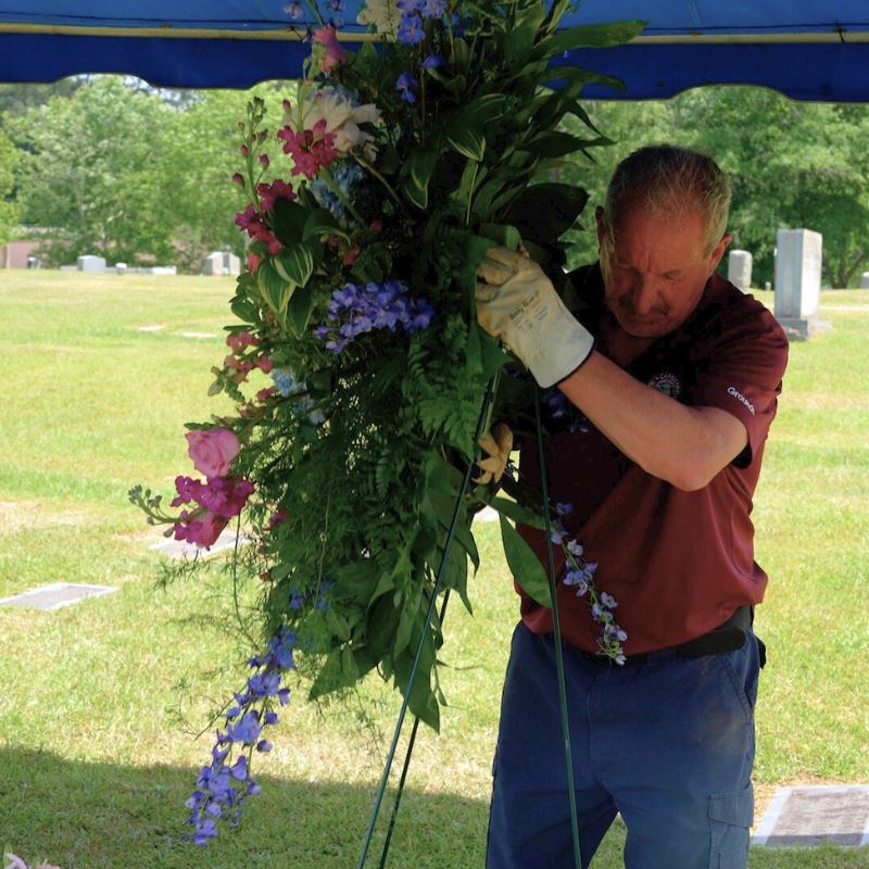 Town of Clayton groundskeeper sets up flowers at a burial site