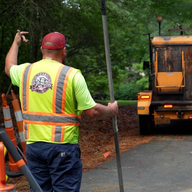 Town of Clayton Street Maintenance worker directs moving work vehicle in road