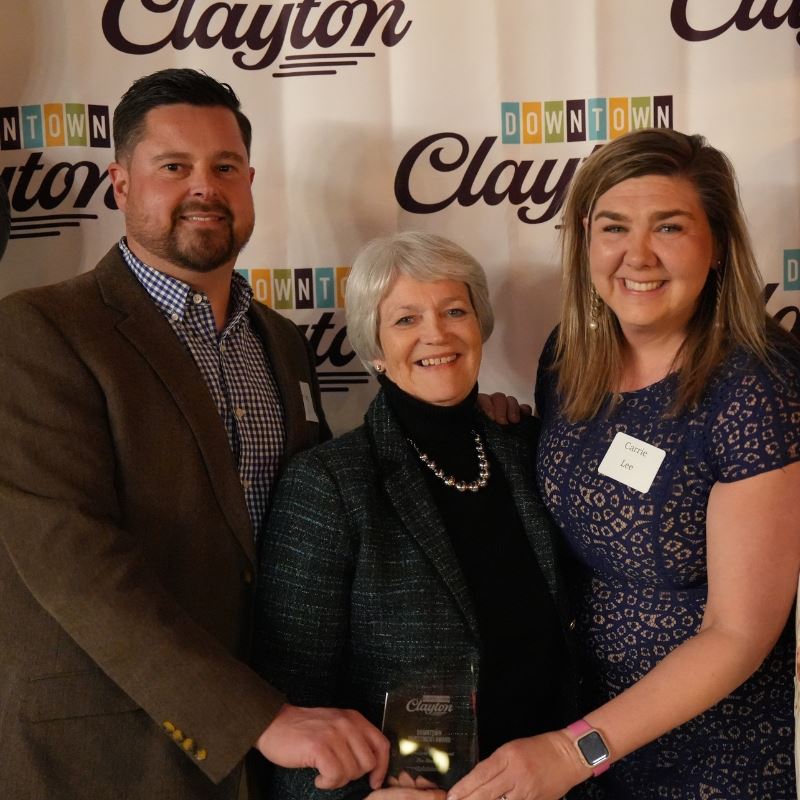 Councilmember Ruth Anderson holds award with The Station owners